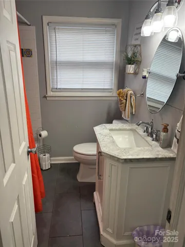 a bathroom with a granite countertop sink a toilet and a mirror