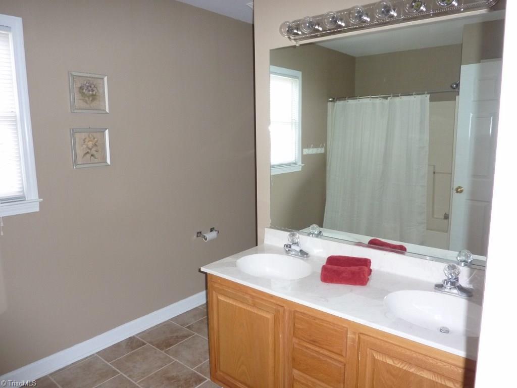 6325 Armsby Road Clemmons, NC 27012 - Photo 22 of 30 Upstairs Hall Bath with double sinks, tile flooring, and tub/shower combination.