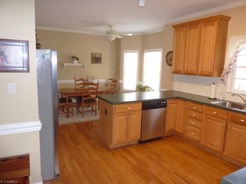 6325 Armsby Road Clemmons, NC 27012 - Photo 10 of 30 Kitchen with lots of storage, hardwoods, breakfast bar, tile backsplash, and crown & chair molding.