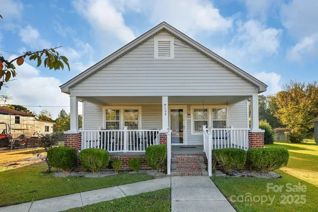 a view of a house with a small yard plants and large tree