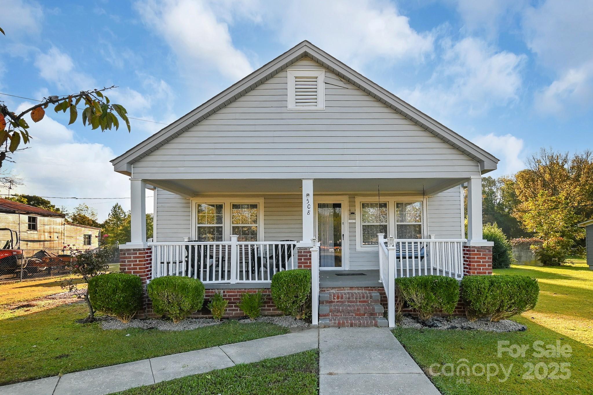 a view of a house with a small yard plants and large tree