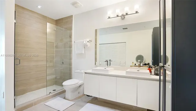 a bathroom with a double vanity sink toilet mirror and shower