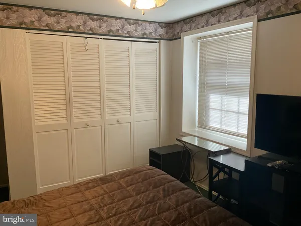 a bedroom with a bed and a flat tv screen next to a window