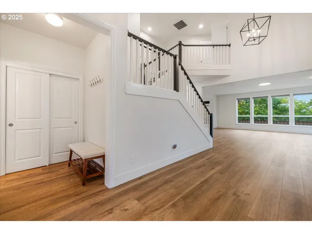a view of an empty room with wooden floor and windows