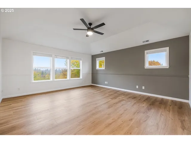 a view of an empty room with window and wooden floor