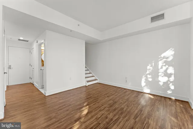 a view of an empty room with wooden floor and doors