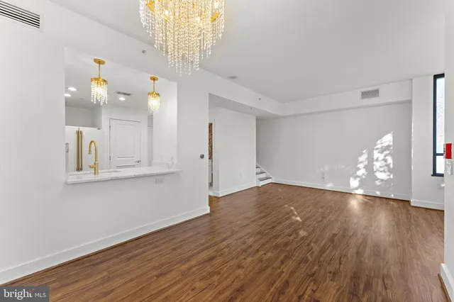 a view of an empty room with glass window and hardwood floor