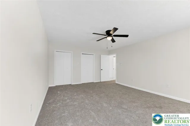 an empty room with fan and windows