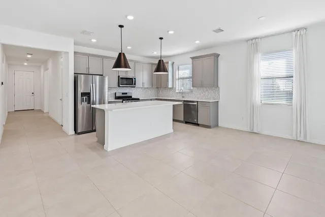 a large kitchen with stainless steel appliances granite countertop a stove and a refrigerator