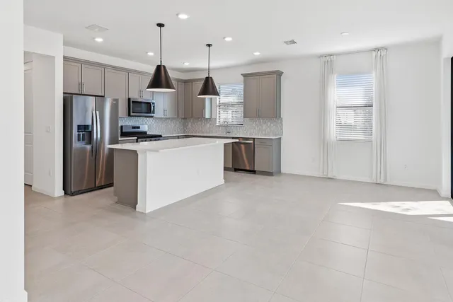 a large kitchen with stainless steel appliances kitchen island granite countertop a refrigerator a sink a stove and oven