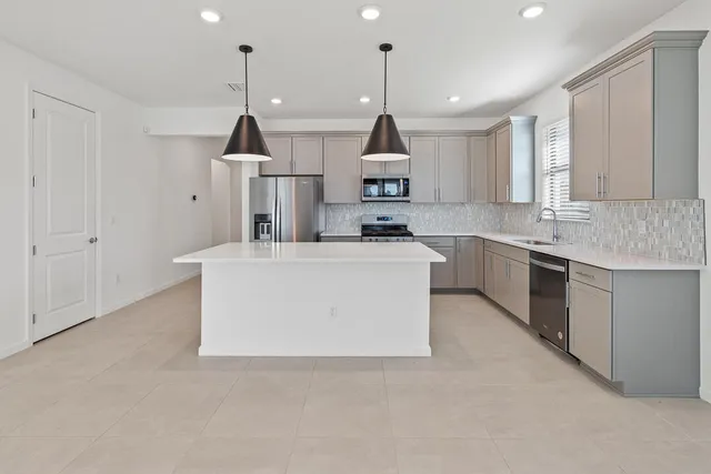 a kitchen with stainless steel appliances granite countertop a sink a stove a refrigerator and white cabinets