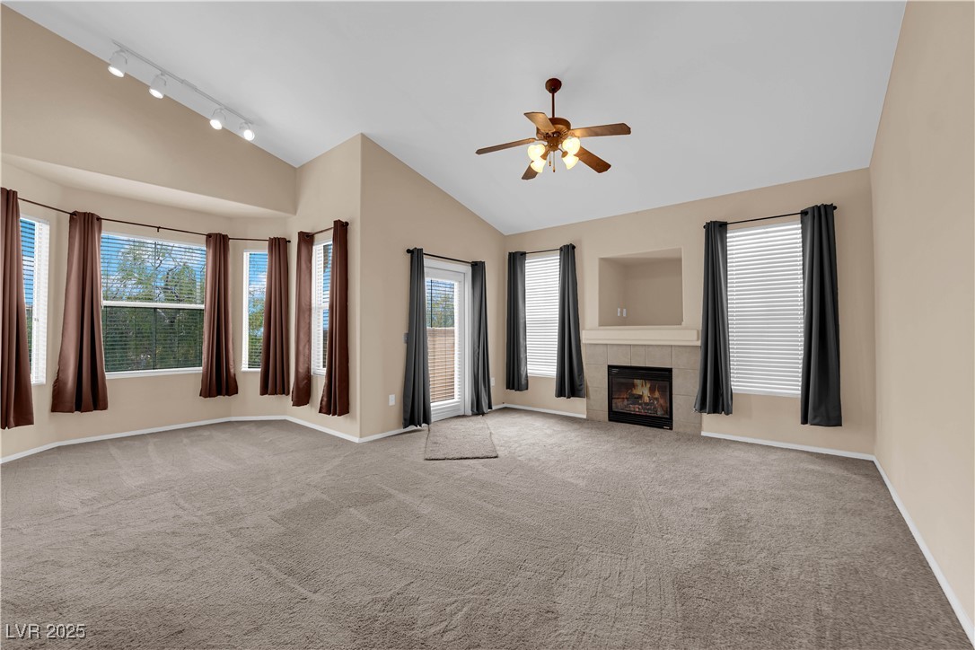 10550 West Alexander Road, Unit 2233 Las Vegas, NV 89129 - Photo 11 of 35 Unfurnished living room with carpet, a ceiling fan, a fireplace, track lighting, and lofted ceiling
