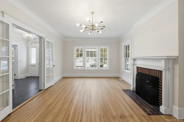 a view of an empty room with wooden floor fireplace and a window
