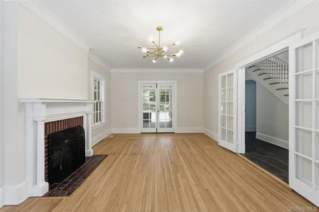a view of an empty room with wooden floor fireplace and a window