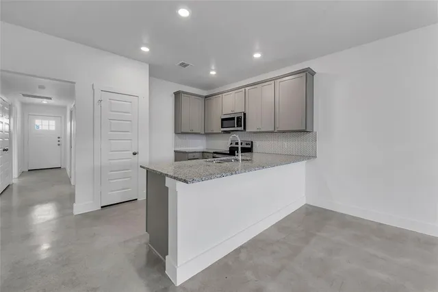 a view of a kitchen with a sink and dishwasher a refrigerator with white cabinets