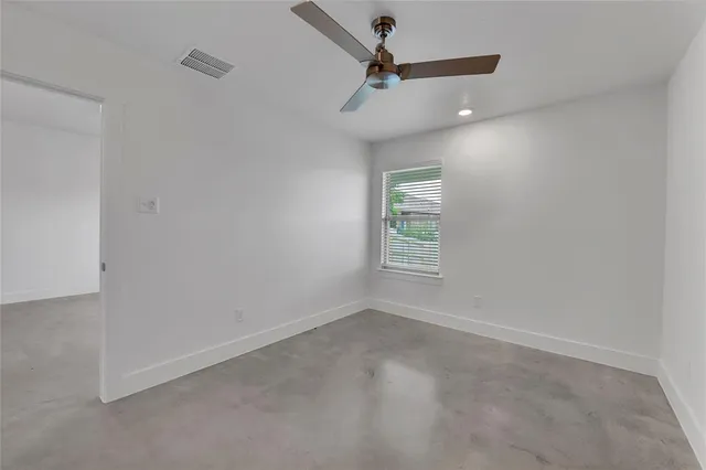 an empty room with windows and ceiling fan
