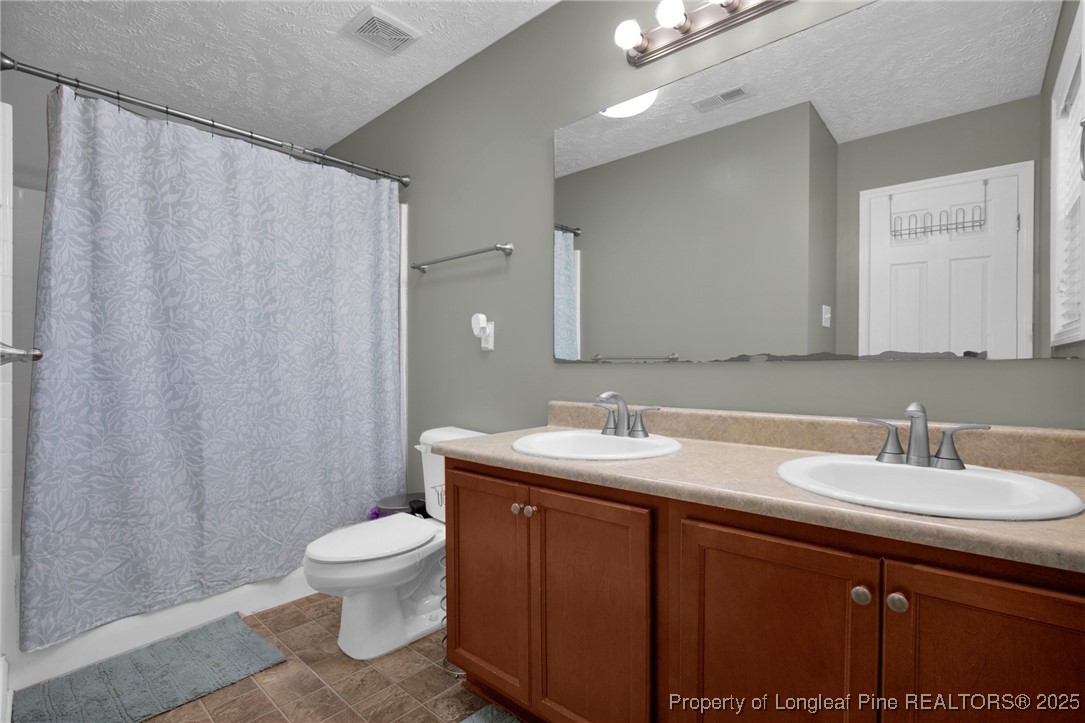 674 Copper Creek Drive Raeford, NC 28376 - Photo 11 of 20 a bathroom with a double vanity sink toilet and a mirror