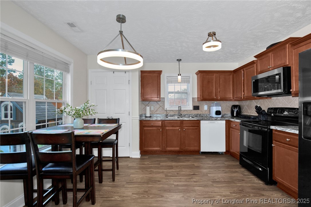 674 Copper Creek Drive Raeford, NC 28376 - Photo 7 of 20 a kitchen with granite countertop wooden floors a stove a microwave a dining table and chairs