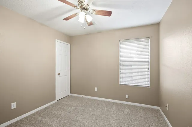 an empty room with windows and fan