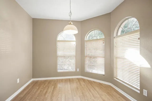a view of an empty room with a window and wooden floor