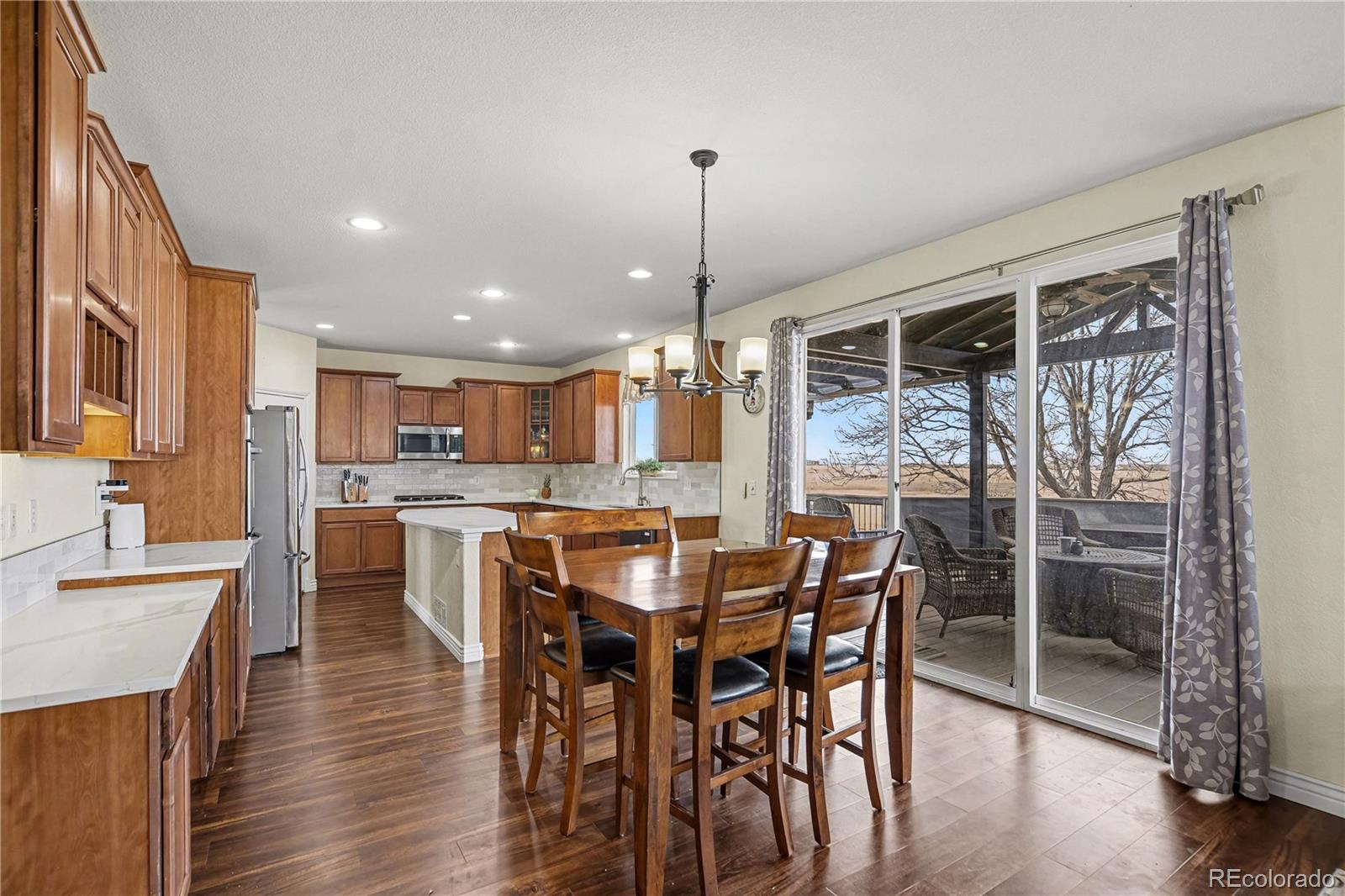 10871 Chambers Way Commerce City, CO 80022 - Photo 13 of 50 a dining hall with stainless steel appliances a dining table chairs and wooden floor