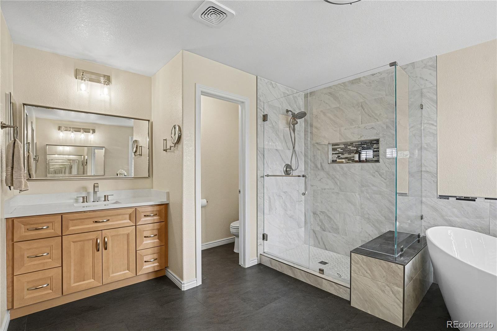 10871 Chambers Way Commerce City, CO 80022 - Photo 21 of 50 a spacious bathroom with a granite countertop sink a mirror a bathtub and shower