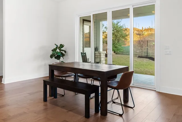 a kitchen with a stove a sink a microwave oven a dining table and chairs with wooden floor