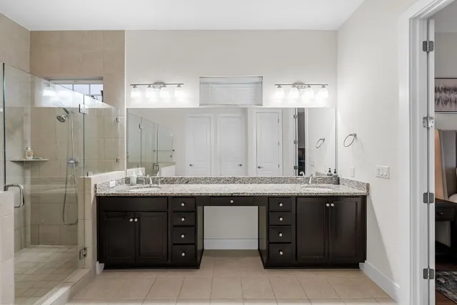 a large bathroom with a granite countertop double vanity sink a large mirror and a bathtub