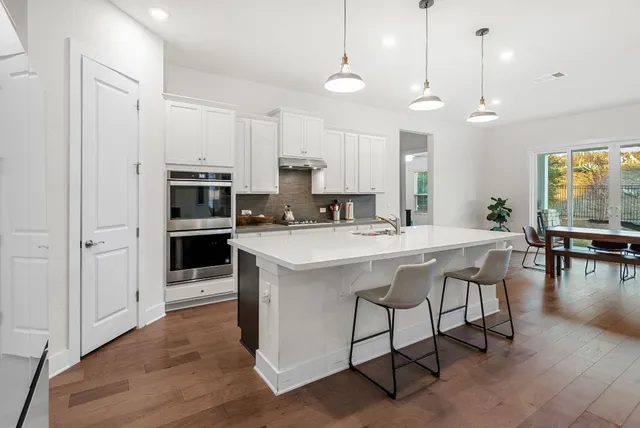 a kitchen with kitchen island granite countertop a sink a counter top space appliances and cabinets