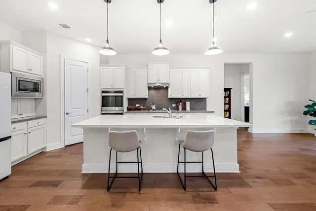 a kitchen with stainless steel appliances kitchen island granite countertop a table chairs sink and cabinets