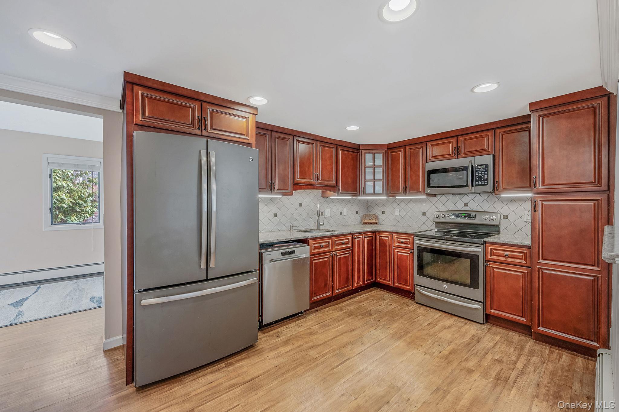 5 Valley Circle Miller Place, NY 11764 - Photo 12 of 38 a kitchen with granite countertop stainless steel appliances a refrigerator cabinets and a wooden floor