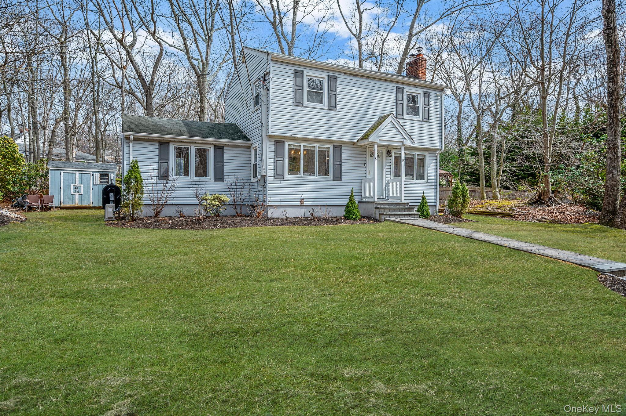 5 Valley Circle Miller Place, NY 11764 - Photo 4 of 38 a front view of a house with a yard and trees