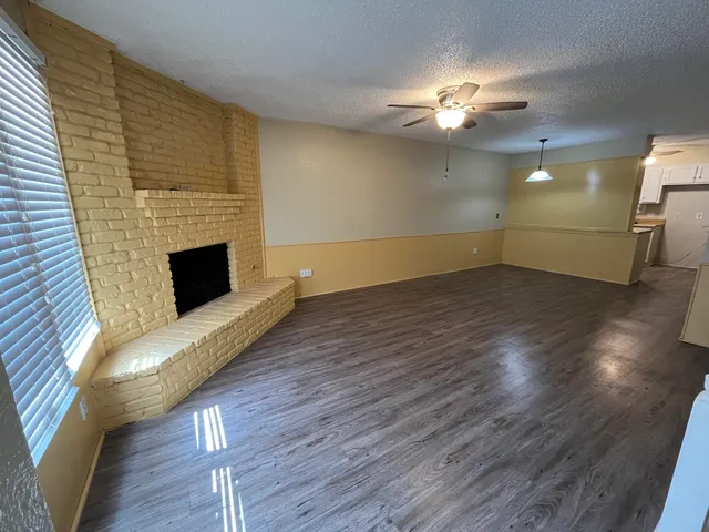 a view of a livingroom with wooden floor a ceiling fan and staircase