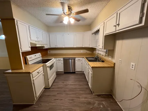 a kitchen with granite countertop a sink a counter top space cabinets and stainless steel appliances