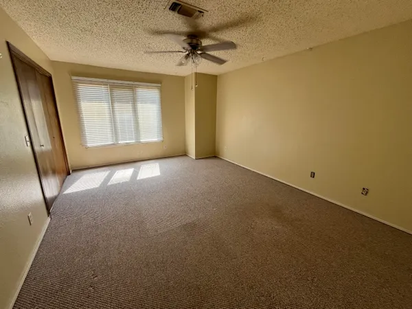 an empty room with a window and a fan