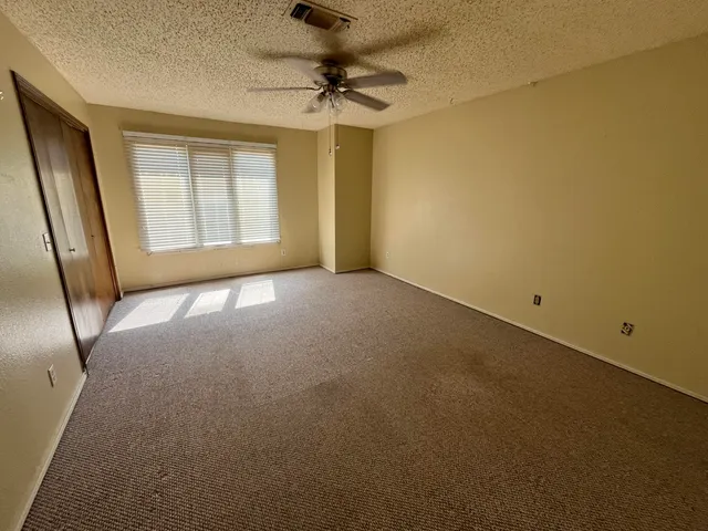 an empty room with a window and a fan