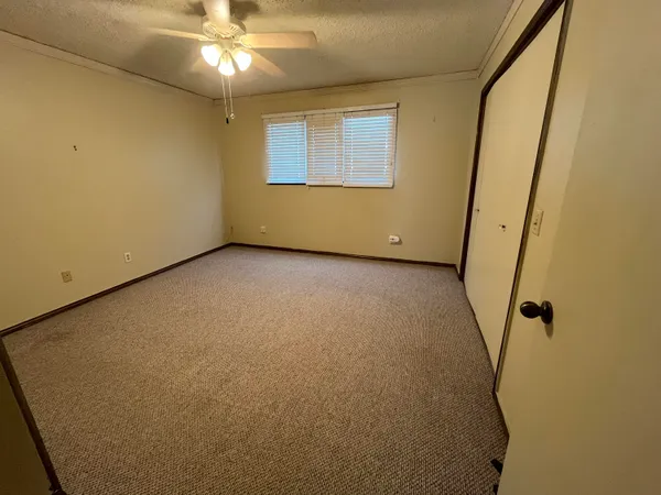 an empty room with a chandelier fan and windows
