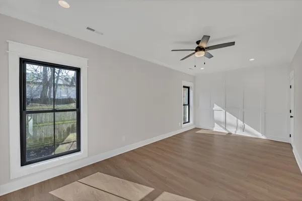 a view of empty room with wooden floor and fan