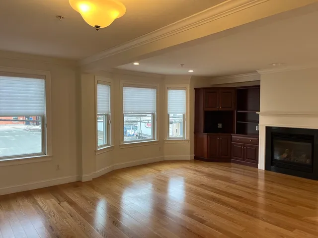 a view of an empty room with window and wooden floor