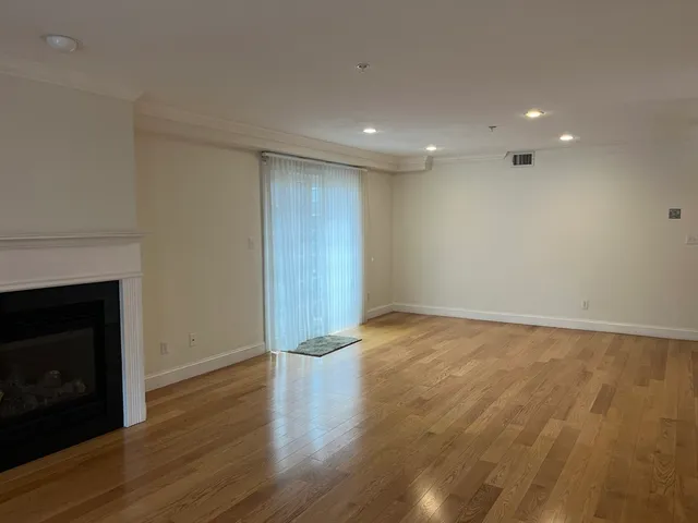 a view of empty room with wooden floor and fireplace