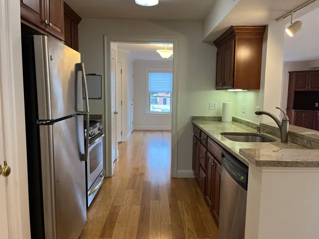 a kitchen with stainless steel appliances granite countertop a refrigerator a sink and wooden floor