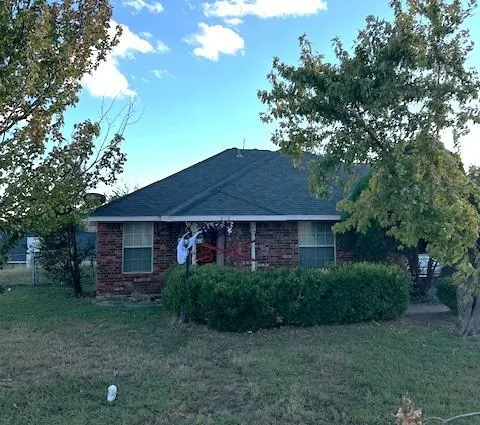 a view of a brick house next to a yard with large trees