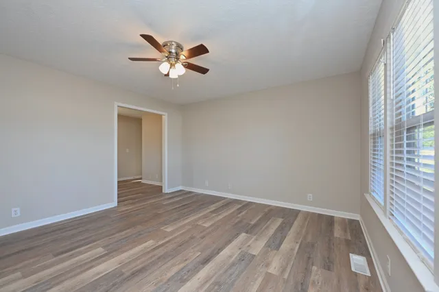 a view of empty room with wooden floor and fan