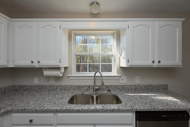 a kitchen with granite countertop a sink dishwasher and cabinets