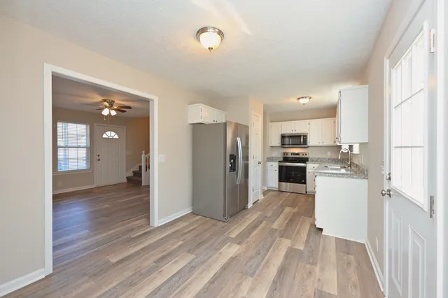 a view of a kitchen with refrigerator and wooden floor