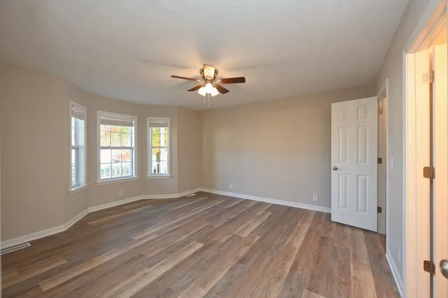 a view of an empty room with chandelier fan and a window