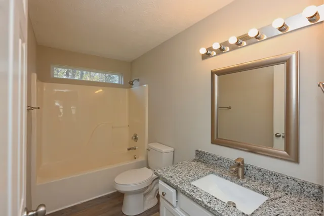 a bathroom with a granite countertop sink mirror vanity and toilet