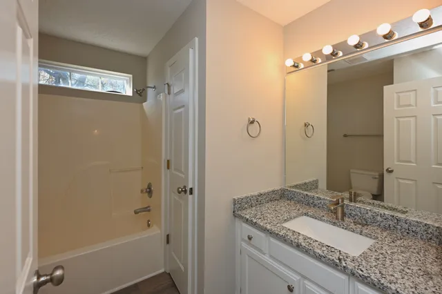 a bathroom with a granite countertop sink tub shower and a mirror