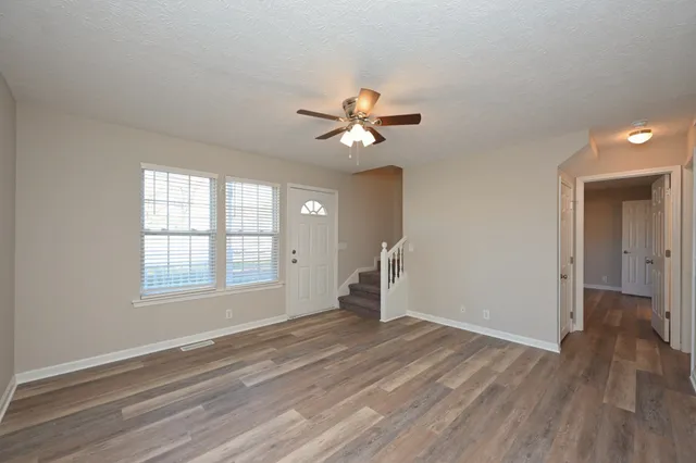 an empty room with wooden floor and windows