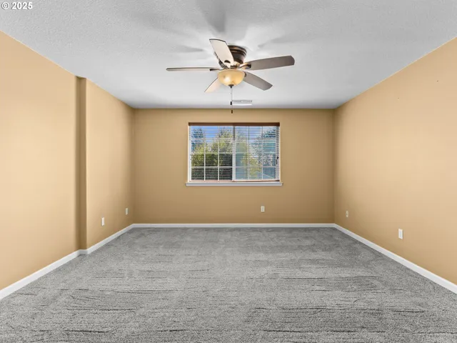 an empty room with a ceiling fan and a window